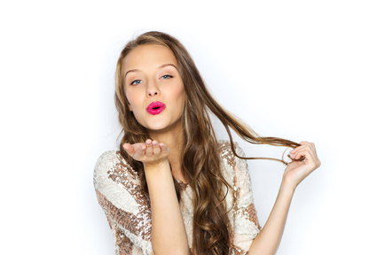 people, style, holidays, hairstyle and fashion concept - happy young woman or teen girl in fancy dress with sequins and long wavy hair sending blow kiss